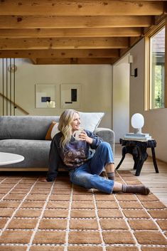 a woman sitting on the floor in front of a couch