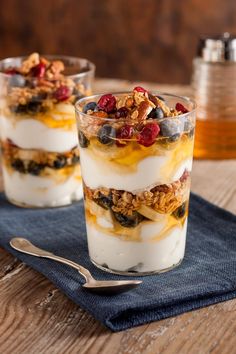 two glasses filled with yogurt and granola on top of a blue napkin