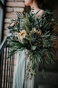 a woman in a dress holding a bouquet of flowers on top of a stair case