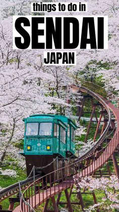 a green train traveling down tracks next to trees with white blossoms on them and the words things to do in sendai japan