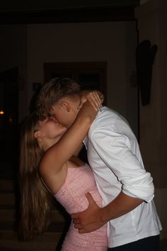 a young man and woman kissing in front of the camera with their arms around each other