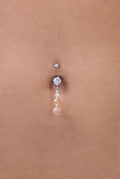 a woman's back with a single diamond and pearl belly ring attached to it