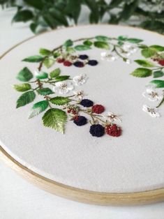 a close up of a embroidery on a white cloth with berries and leaves in it