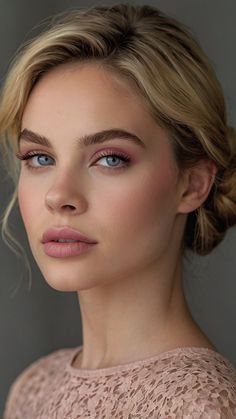 a woman with blonde hair and blue eyes wearing pink eye makeup looks at the camera