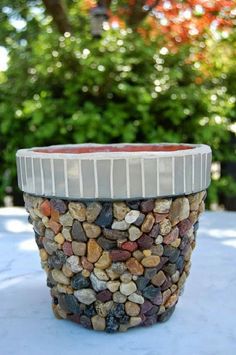 a pot filled with rocks sitting on top of a white tablecloth covered ground next to trees