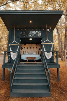 a tiny house with two hammocks hanging from the ceiling and stairs leading up to it