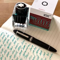 a fountain pen sitting on top of a notepad next to a box of ink