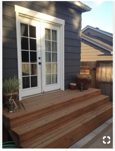 a wooden deck with steps leading to the front door and patio area next to it