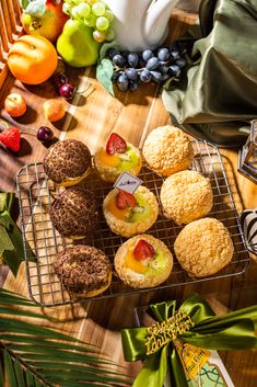 several pastries are on a cooling rack with green ribbons and fruit in the background