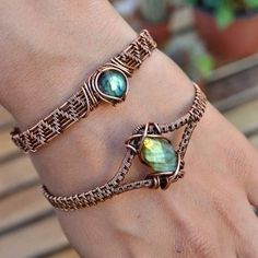 two bracelets with different colored stones on their hands, one is gold and the other is green