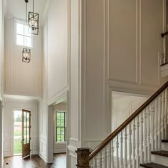 an elegant entry way with wood floors and white walls, chandelier, and wooden stairs