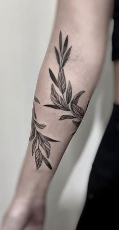 a black and white photo of a person's arm with leaves tattooed on it