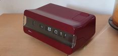 a red alarm clock sitting on top of a wooden table