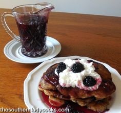 pancakes with blueberries and whipped cream on them are served next to a glass of tea