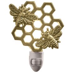 a gold honeycomb with two bees on it's side and an outlet in the middle