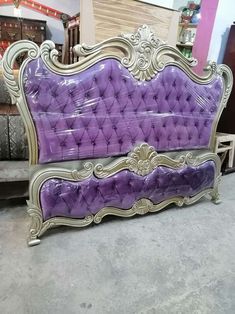 a purple couch sitting on top of a floor next to a pile of furniture in a room