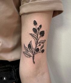 a small black and white flower tattoo on the right inner arm, with leaves in it