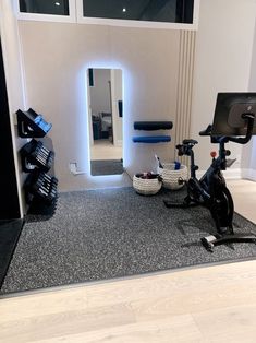 there is a bike and exercise equipment in the room with mirrors on the wall behind it