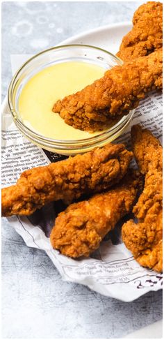 fried chicken sticks with dipping sauce in a glass bowl on a paper towel next to it