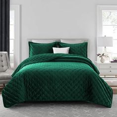 a green comforter set in a white bedroom