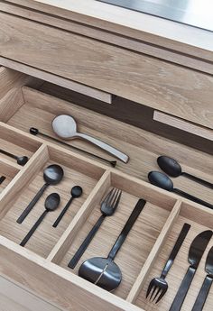 an open drawer with utensils and spoons in it