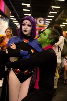 two people dressed up in costumes hugging each other at a convention or show, one person is wearing a costume and the other has purple hair