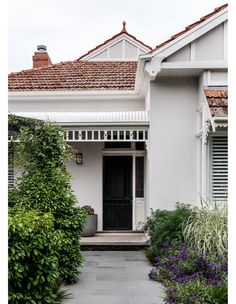 a white house with plants and bushes around it