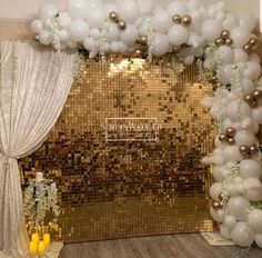 a gold sequin backdrop with white balloons and greenery for a wedding or event