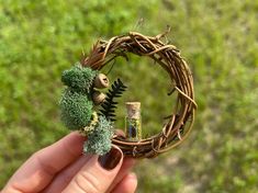 a hand holding a miniature wreath with plants