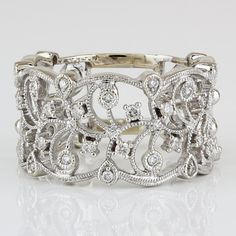 a white gold and diamond bracelet with filigrees in the middle, on a reflective surface