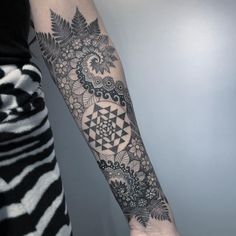 a woman's arm with an intricate tattoo design on the left side of her arm