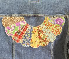 the back of a jean jacket with patchwork and flowered patches on it's pockets