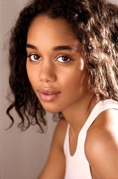 a close up of a person wearing a tank top with curly hair and blue eyes