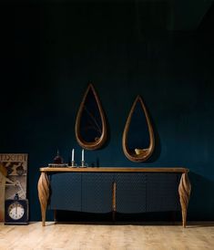 a table with two mirrors and a clock on it in a room that has blue walls