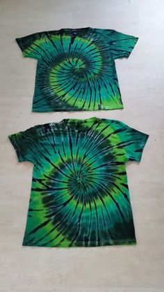 two t - shirts with green and blue swirls on the front, one in black