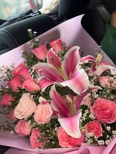 a bouquet of pink and white flowers sitting on top of a car seat in front of a woman