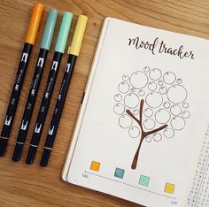 four markers and a notebook with a tree drawn on it