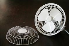 a white fan sitting on top of a wooden table next to a small round object