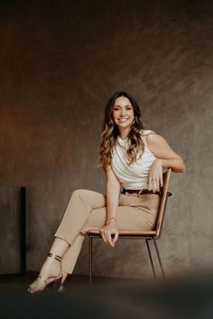 a woman is sitting in a chair and posing for the camera with her legs crossed