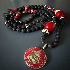 Red Ganesha Pendant Black Beaded Good Luck Necklace; Ganesha is one of the most well-known and revered Hindu deities. He is often associated with success, wisdom, and protection, making this handmade necklace an ideal talisman for anyone seeking these qualities. The black lava rock stone beads are believed to have grounding properties, helping to connect the wearer with the earth and provide a sense of stability and balance. The coral stone add a pop of color and are said to promote harmony and Ganesha Pendant, Luck Necklace, Good Luck Necklace, Yoga Necklace, Buddha Beads, April Birthstone Jewelry, March Birthstone Jewelry, Coral Stone, Hindu Deities