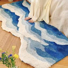 a child is sitting on the floor in front of a rug that looks like waves