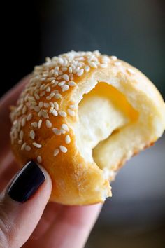 a hand holding a donut with sesame seeds on it and an egg in the middle