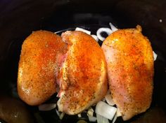 two pieces of chicken in a crock pot with onions and seasoning