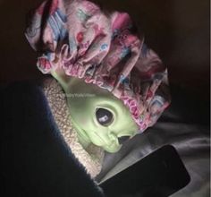 an alien doll wearing a pink hat with flowers on it's head and eyes