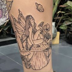 a woman sitting on top of a table with flowers and butterflies around her leg tattoo