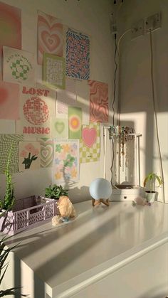 a white dresser topped with lots of clutter next to a wall covered in pictures