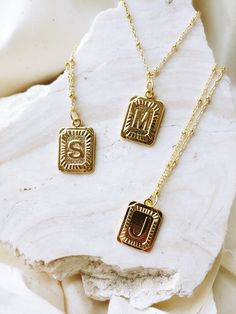 our *pre-order* square pendant initial necklaces are the go-to essential for any look you're pulling these days // each monogram pendant features a design in dimensional relief that has been polished to perfection to sparkle against your skin the pendant measures approximately 1” and comes on an 18” chain with an added extender chain gold plated: this necklace is tarnish resistant, the gold plating receives an additional protective coat that allows for frequent wearing without the worry of your Letter Necklace Initials, Square Pendant Necklace, Gold Pendent, Dainty Initial Necklace, Monogram Pendant, Mobile Boutique, Letter Pendant Necklace, Initial Necklace Gold, Initial Pendant Necklace