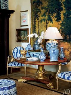 a blue and white table with vases on it in front of a large painting