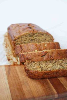 sliced banana bread sitting on top of a wooden cutting board next to a loaf of bread