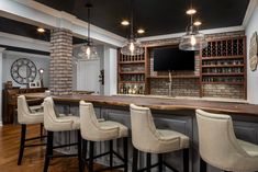 a bar with four stools in front of it and a television on the wall